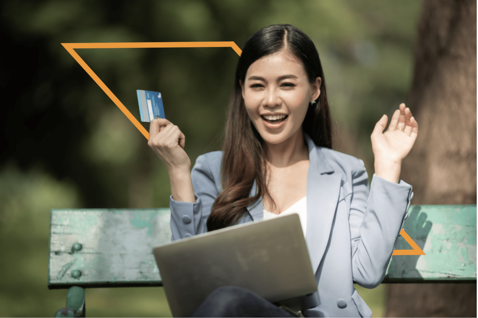 A woman sitting on the ground holding a laptop and credit card.